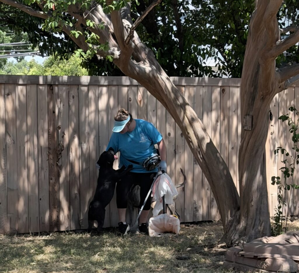 Pet waste technician greeting dog during cleanup