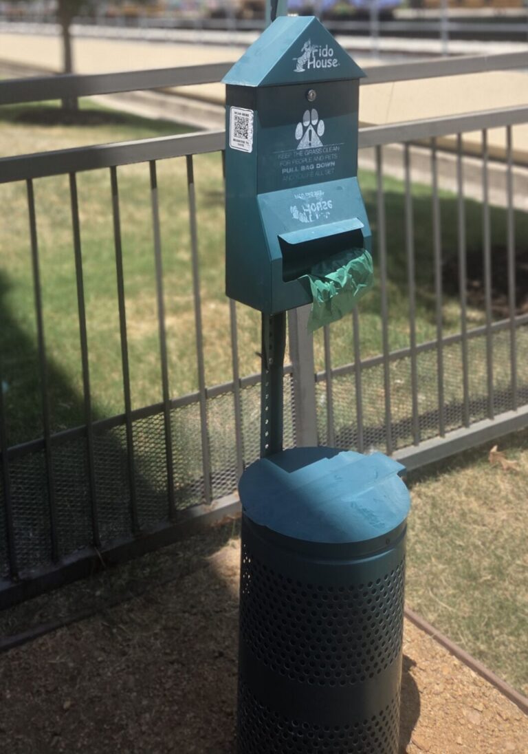 pet waste station sits near a dog park at an apartment complext